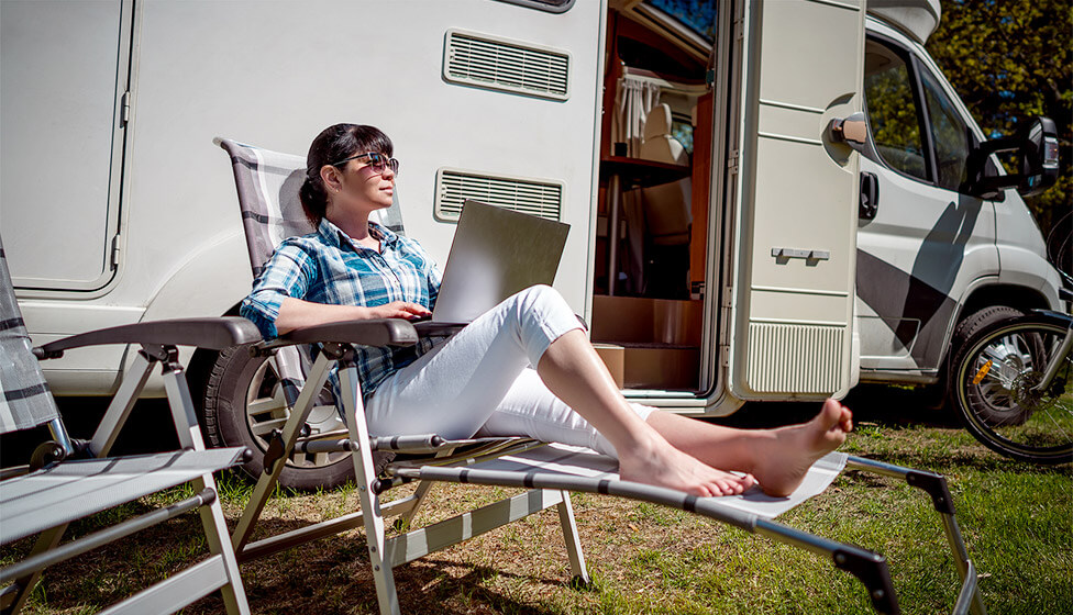 Woman on laptop outside motorhome